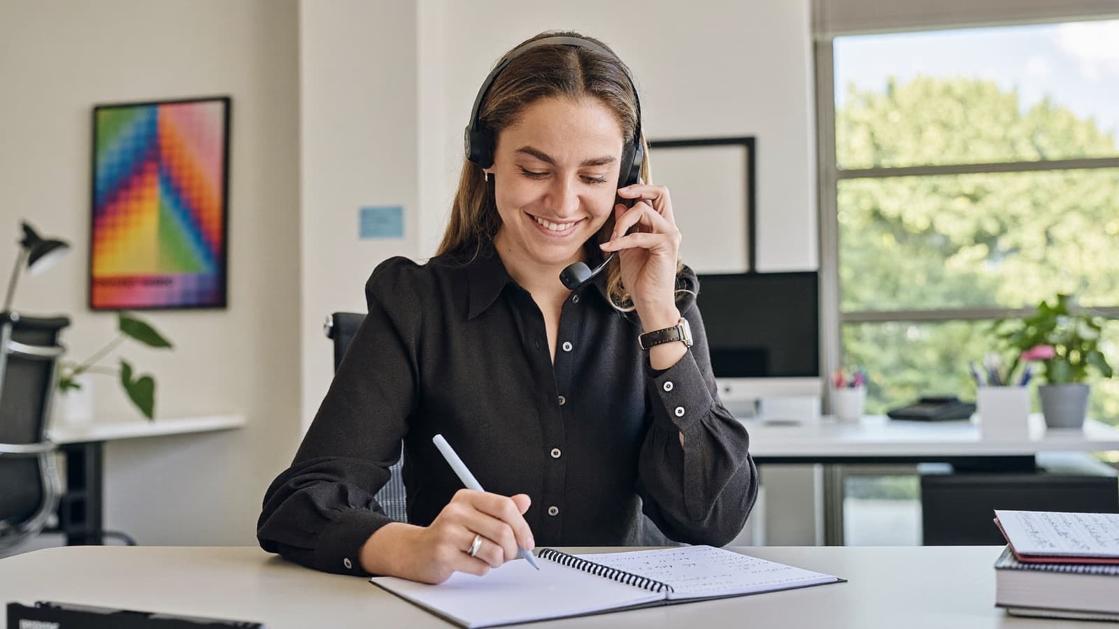 A licensed Liberty Health advisor on a call, taking notes on a plan comparison