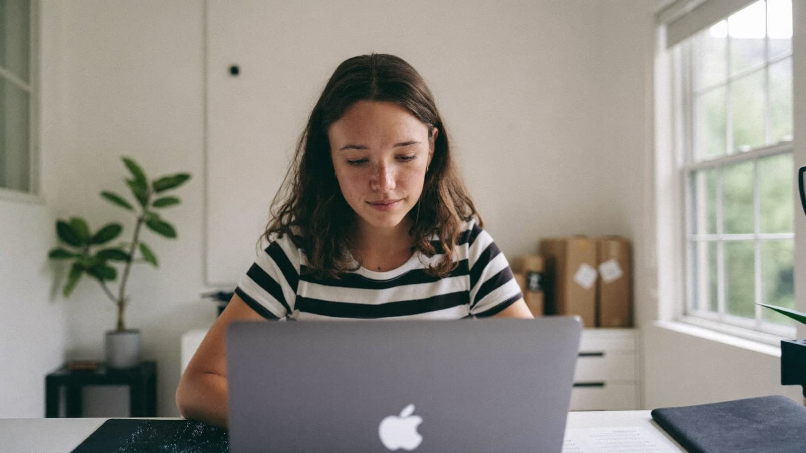 A young founder working at a laptop in a small studio workspace