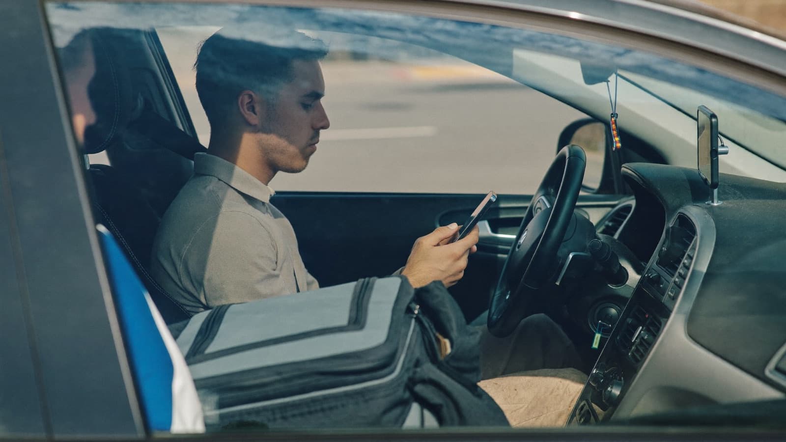 A gig-economy driver checking his phone in his parked car