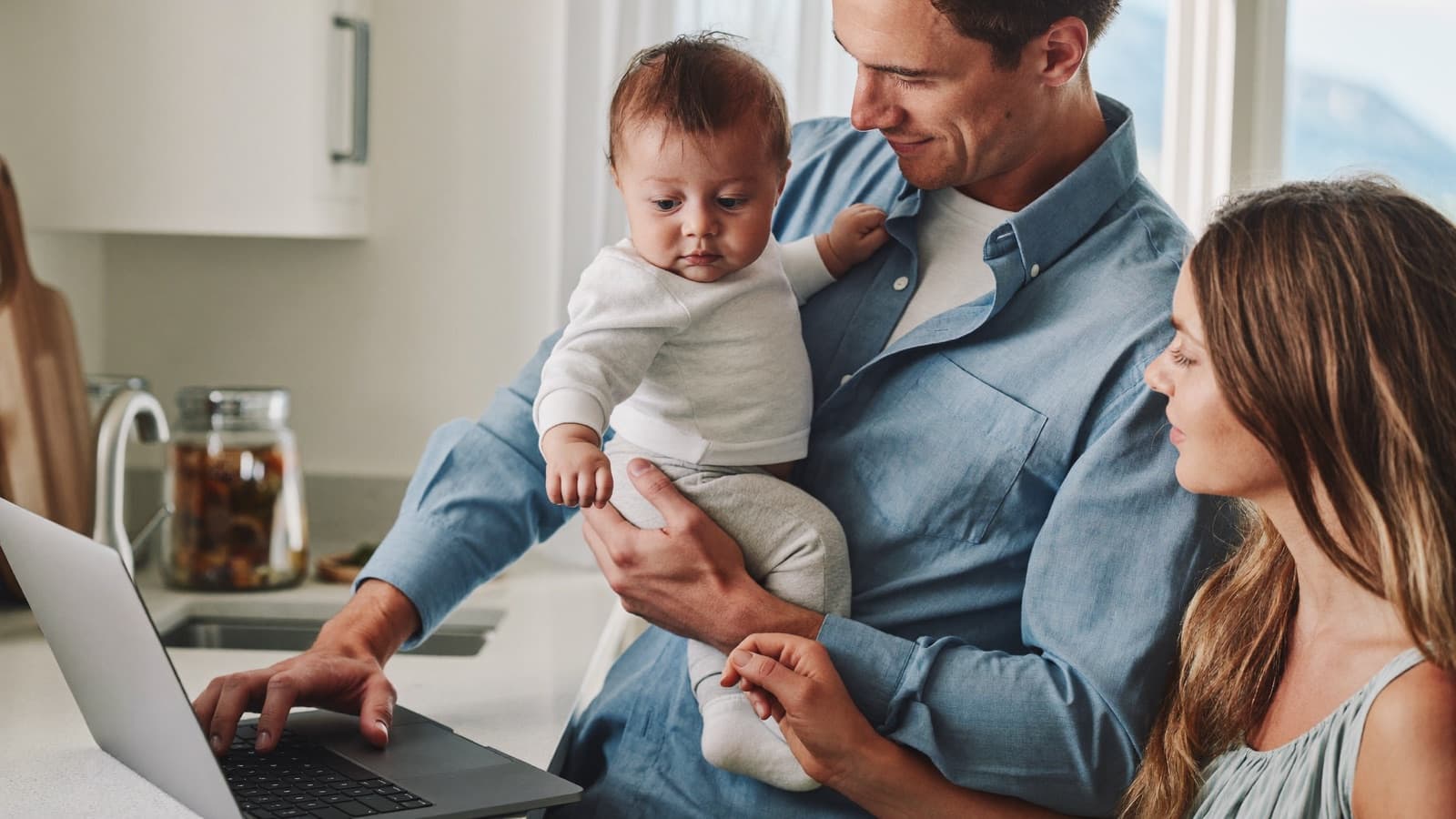 Young parents with their baby comparing coverage options on a laptop at home