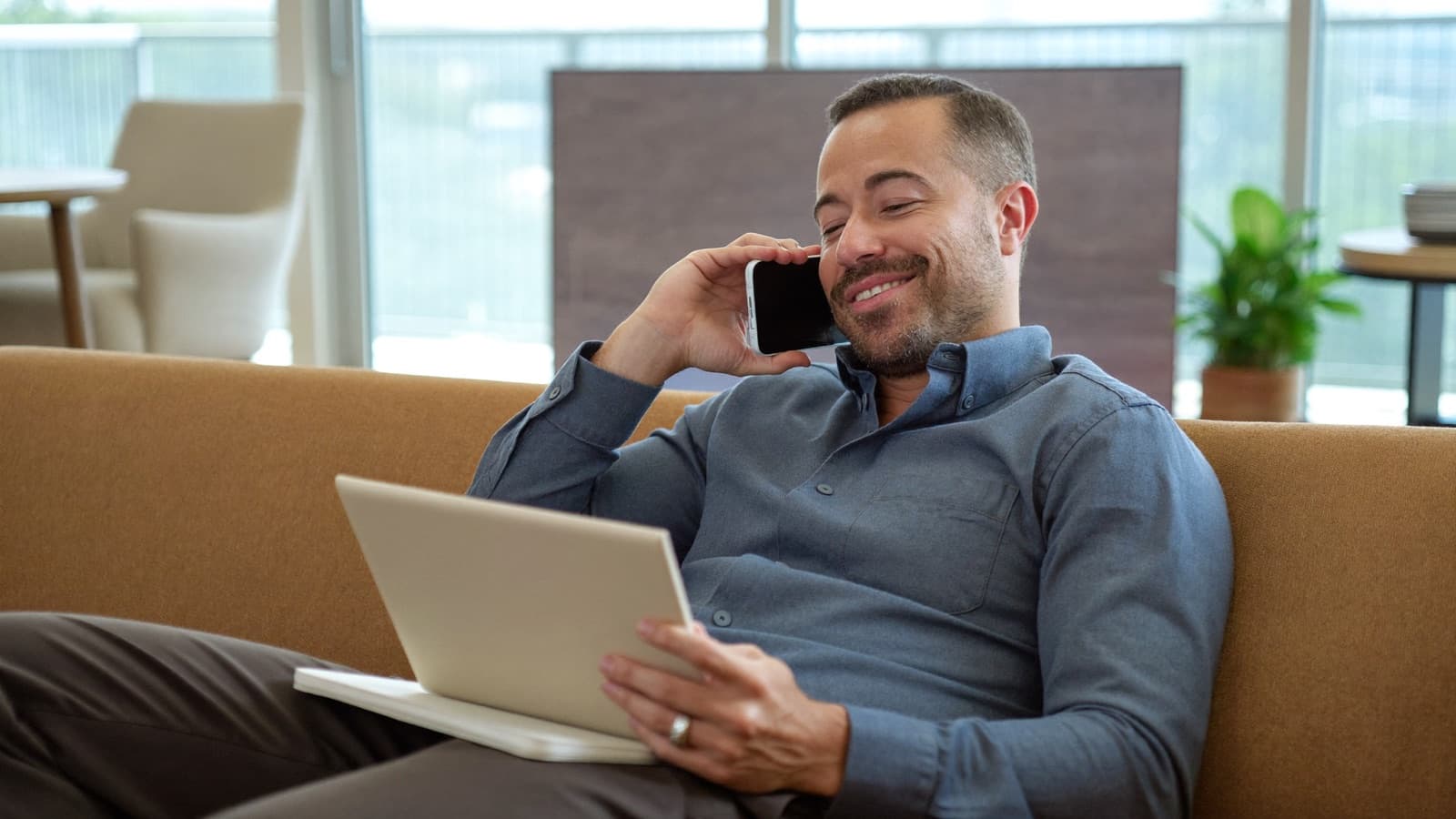 A man at home on the phone with an advisor, notepad on his knee